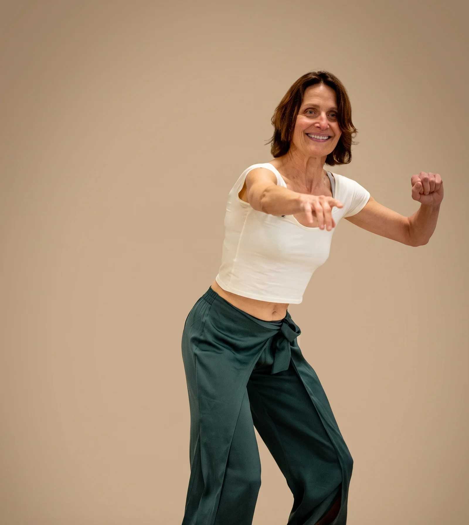 Laurence Arpi en mouvement dans une salle de formation, tee-shirt blanc et pantalon vert